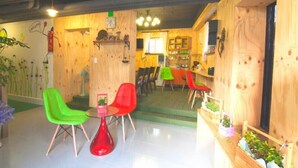 Un interior acogedor con paredes de madera, una silla verde, una silla roja y una pequeña mesa.