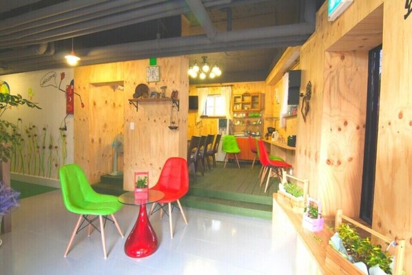 A cozy interior with wooden walls, a green chair, a red chair, and a small table. - Jeonjuhanokvillage guesthouse (Jeonju)