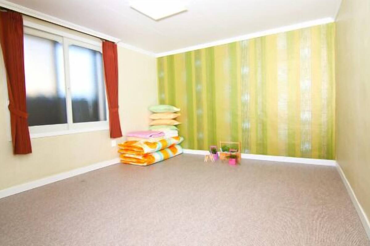 A room with a window, a stack of folded blankets, and a green striped wall.