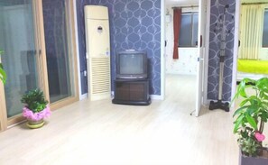 A room with a television, a sliding door, a small table, and a potted plant. - Jeonjuhanokvillage guesthouse (Jeonju)