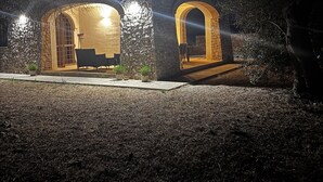 Um edifício de pedra com duas arcadas iluminadas e um pequeno pátio com mesas ao ar livre.