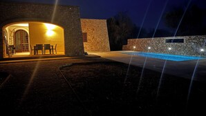 Edifício de pedra com porta em arco e área de piscina.