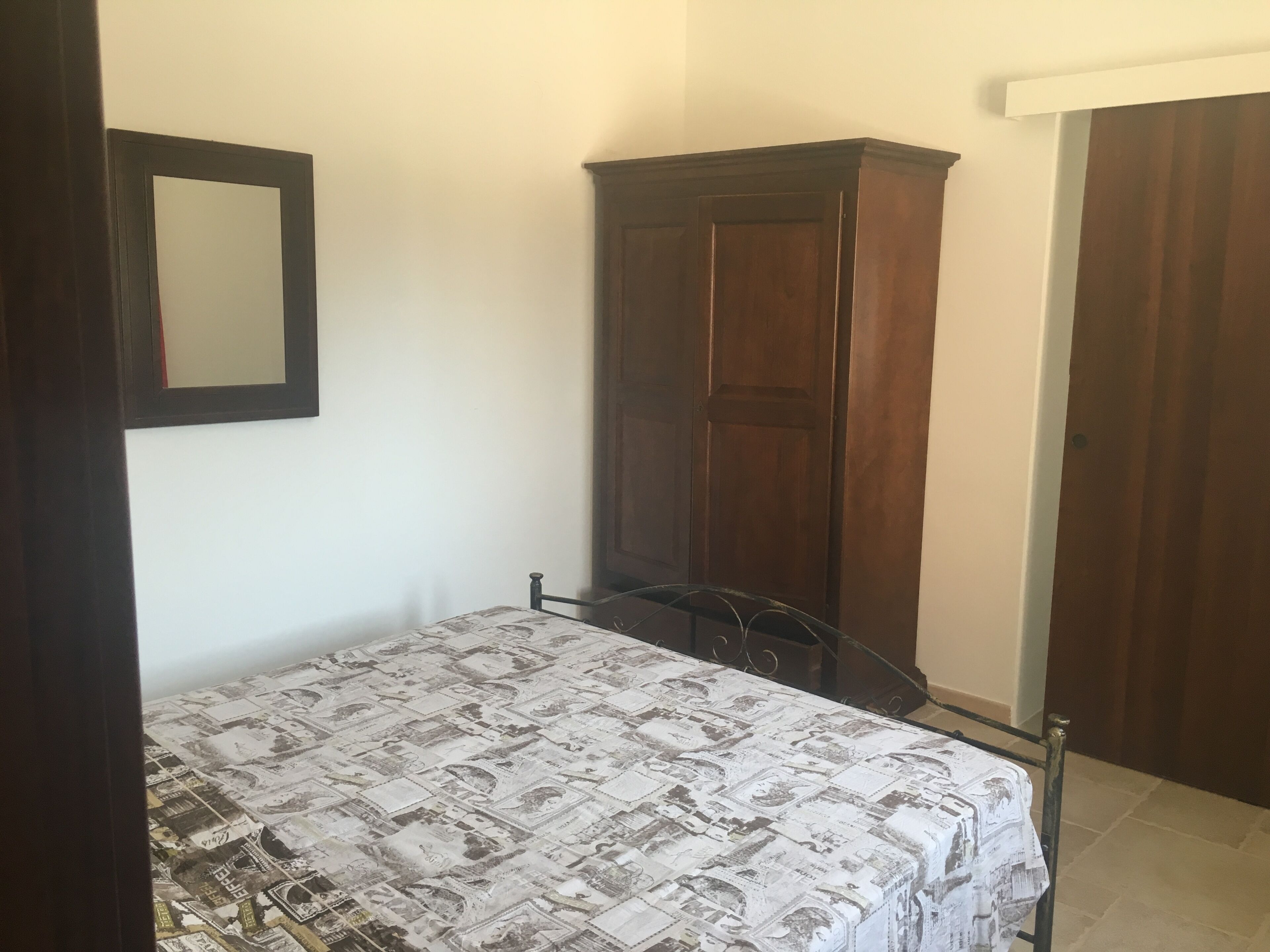 Une chambre à coucher avec un lit, une armoire et un miroir au mur.