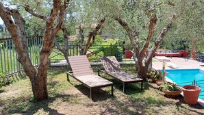 A backyard with a pool, two lounge chairs, and a red building. - Detached house with large private pool for exclusive use (Riano, Roma)