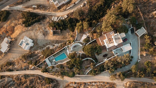 An aerial view of a property with a swimming pool, multiple buildings, and surrounding vegetation. - Spacious, private luxury villa with pool, & stunning sea and sunset views (Glinado)