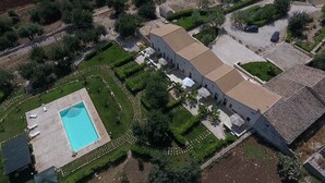 An aerial view of a property with a swimming pool, a courtyard with seating, and a large building with a tiled roof. - AGRITURISMO I5SENSI (Vc) Studio of 45 square meters, with swimming pool. (Modica)