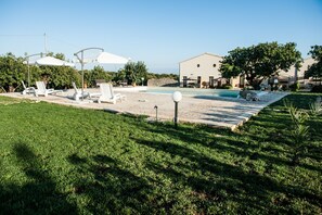A swimming pool area with lounge chairs and umbrellas.