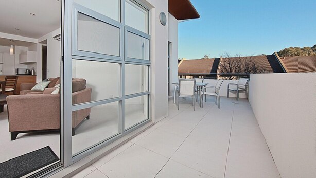 Eine moderne Wohnung mit einer Glastür, die auf einen Balkon mit Sitzgelegenheit führt.