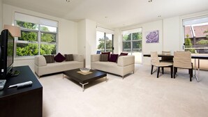 Ein modernes Wohnzimmer mit zwei Sofas, einem Couchtisch und einem Essbereich mit Stühlen.