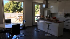 Une cuisine moderne dotée d’un îlot central, de tabourets de bar et d’un coin repas avec une table et des chaises.