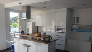 Une cuisine moderne dotée d’un îlot central, de meubles blancs et d’un four à micro-ondes.