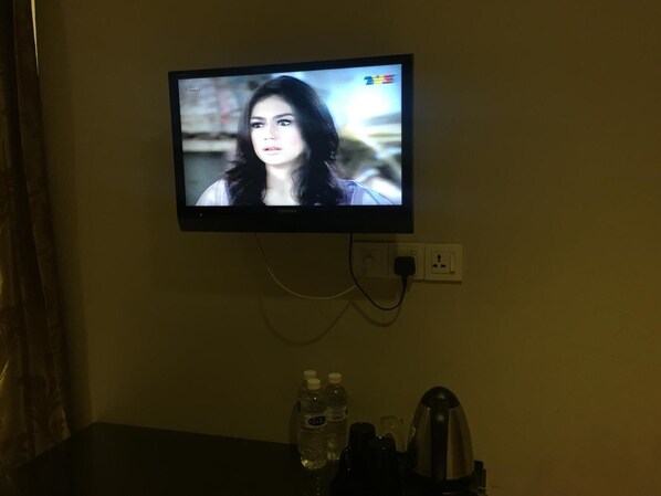 A television mounted on a wall displaying a scene with a person.