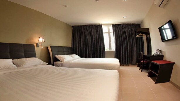 A hotel room with two beds, a desk, a TV, and a window with curtains. - Ayer Hitam Hotel (Ayer Hitam)