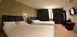 A hotel room with two beds, a desk, a TV, and a window with curtains.