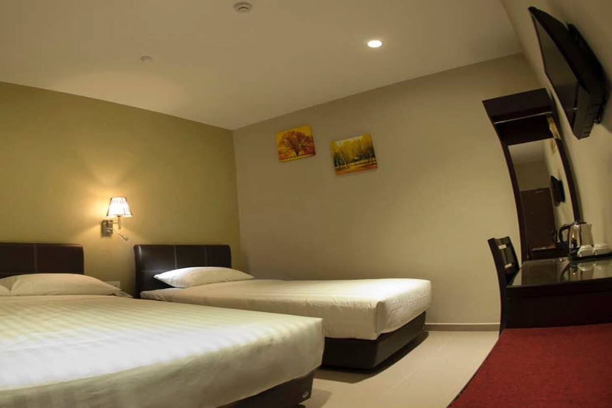 A hotel room with two beds, a desk, a mirror, and a TV.
