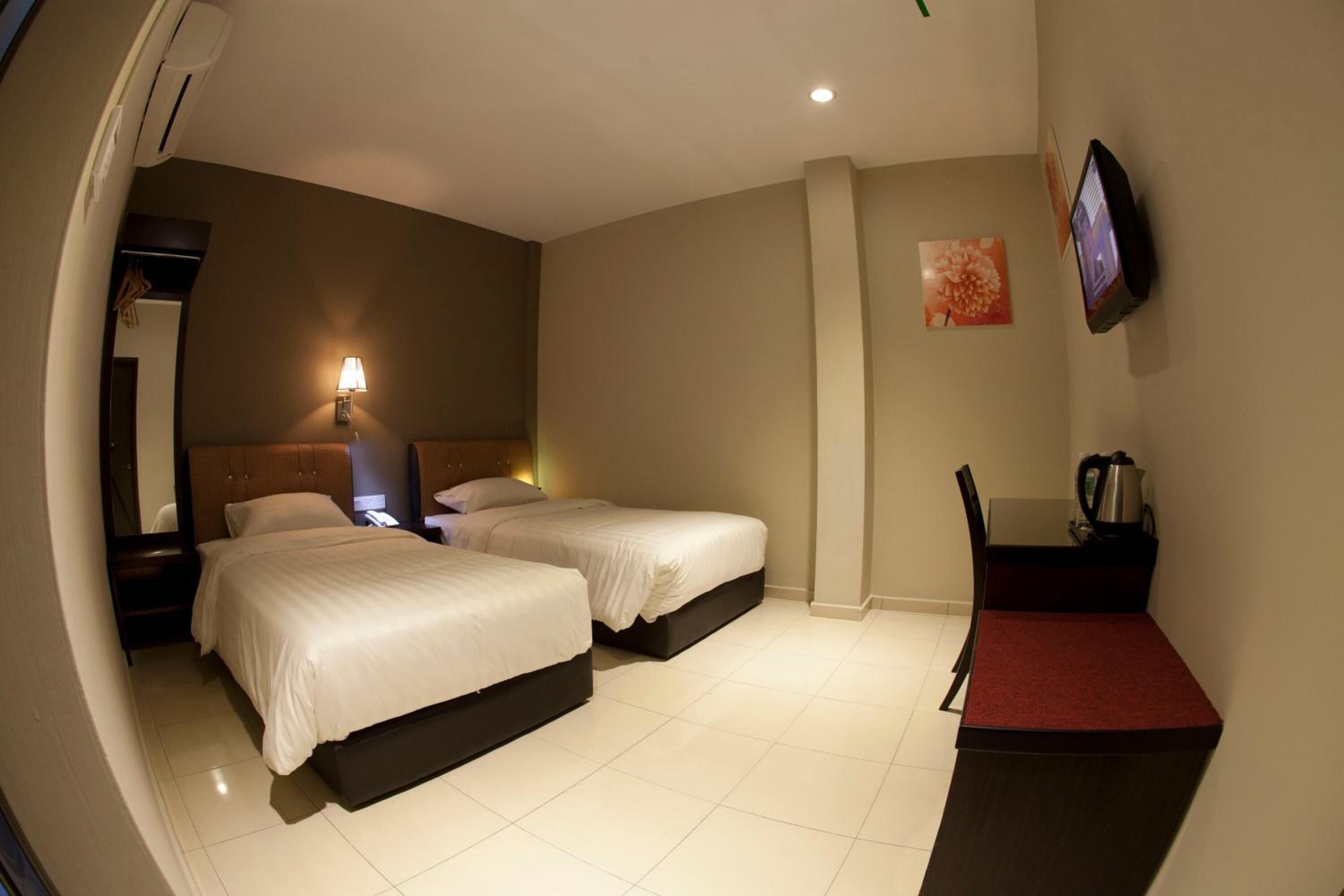 A hotel room with two beds, a desk, a TV, and a coffee maker.