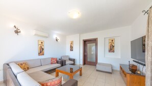 Una sala moderna con un sofá gris, una mesa de centro de madera y un televisor sobre un mueble de madera.