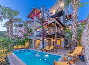 A multi-story building with a pool, outdoor seating, and balconies. - Villa Tara With Private Pool And Sea Views Close to Beach & Shops (Kalkan)
