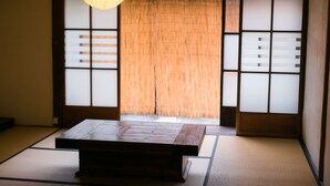 A traditional Japanese room with tatami flooring, a low wooden table, and sliding shoji doors. - Guesthouse OKI's Inn - Hostel (Kyoto)