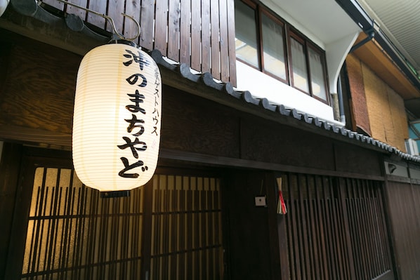 Un edificio japonés tradicional con fachada de madera y un farolillo de papel colgante con caracteres japoneses.