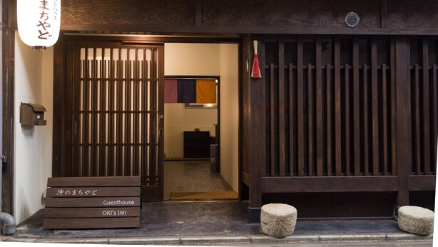 A traditional Japanese inn entrance with a wooden gate, a signboard, and a bench outside. - Guesthouse OKI's Inn - Hostel (Kyoto)