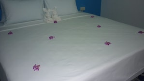 A neatly made bed with white bedding and purple flower petals. - Maneemudjalin Resorts Farm Stay (Sam Roi Yot)