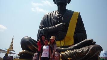 Una estatua grande de una figura sentada con un cinturón amarillo, rodeada por una multitud.