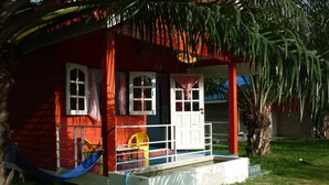 A red building with white windows and a white door, surrounded by greenery. - Maneemudjalin Resorts Farm Stay (Sam Roi Yot)