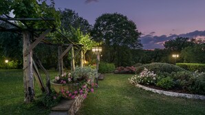 Een tuin met een pergola, plantenpotten en een verzorgd gazon.