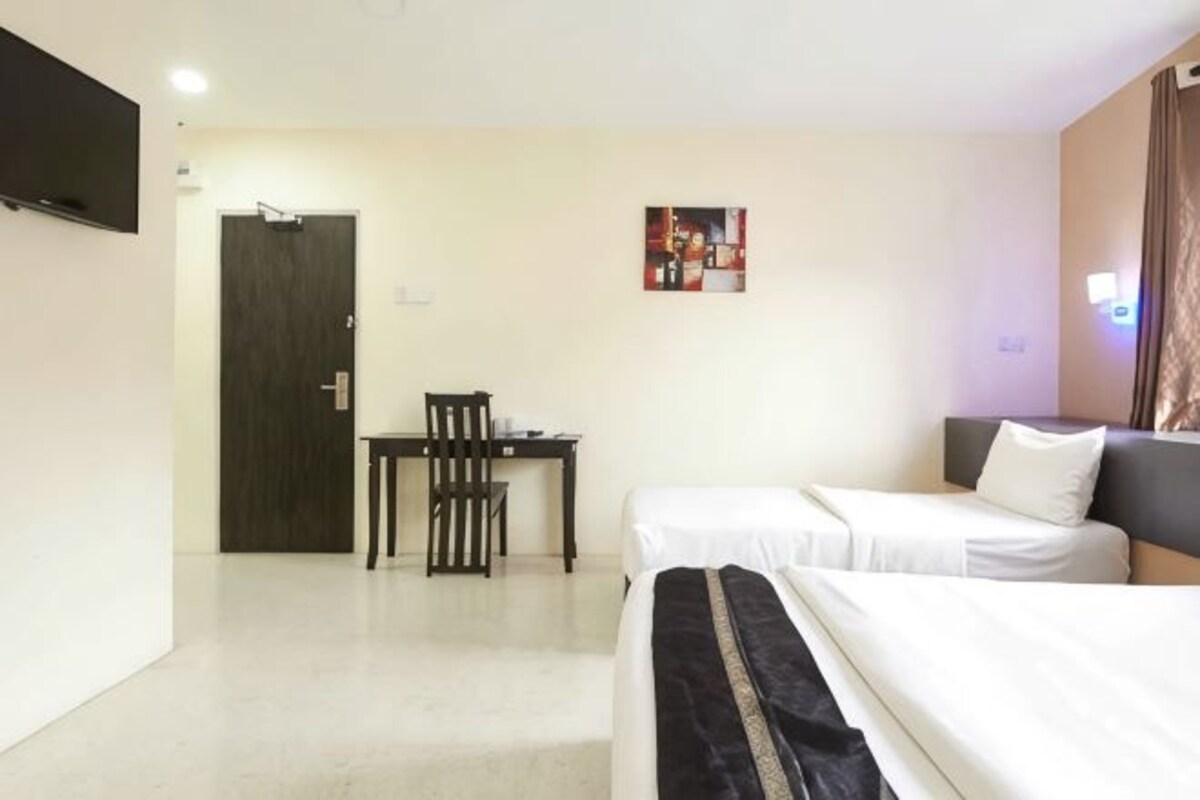 Une chambre d’hôtel avec deux lits, un bureau, une chaise, une télévision et une porte.