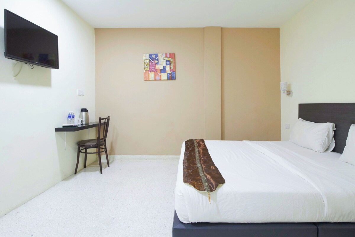 Une chambre d’hôtel comprenant un lit, un bureau avec une chaise, un téléviseur fixé au mur et une petite œuvre d’art accrochée au mur.