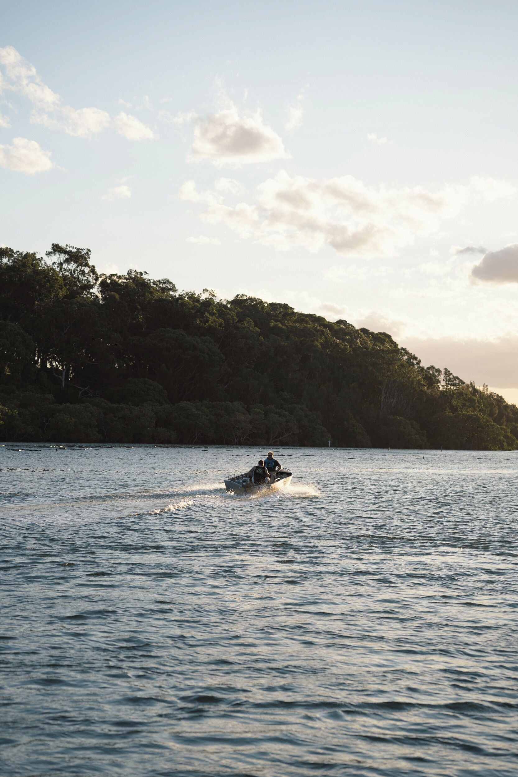 Un jet ski sobre un lago tranquilo con una orilla boscosa al fondo.