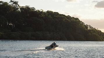 Un jet ski sobre un lago tranquilo con una orilla boscosa al fondo.