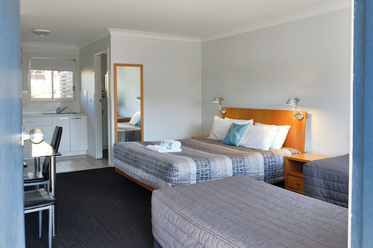 A hotel room with a bed, a desk, and a mirror.