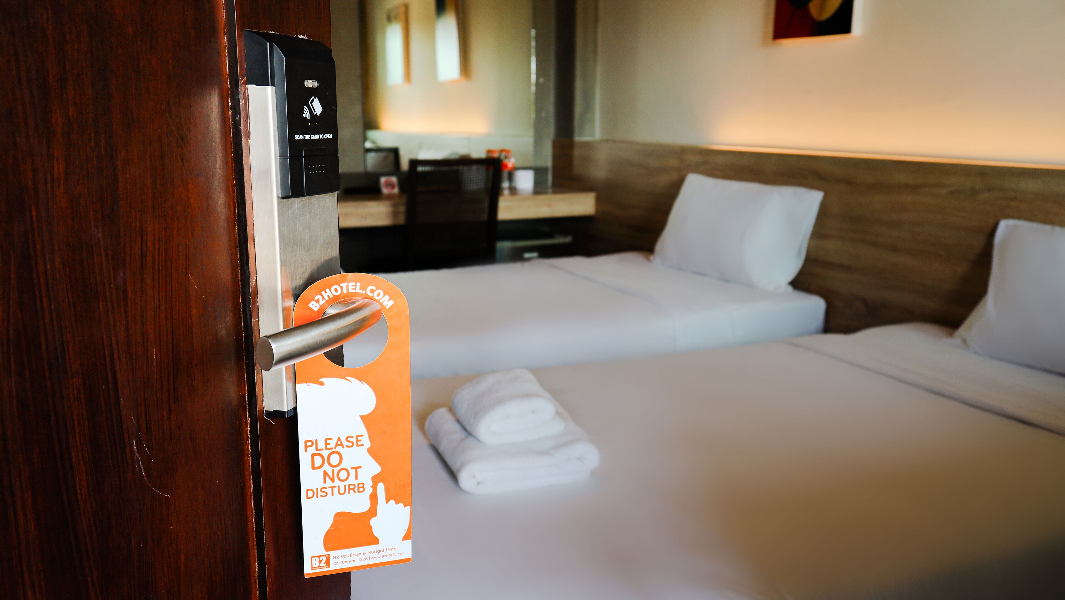 A hotel room with a bed, a bedside table, and a card reader for card entry.