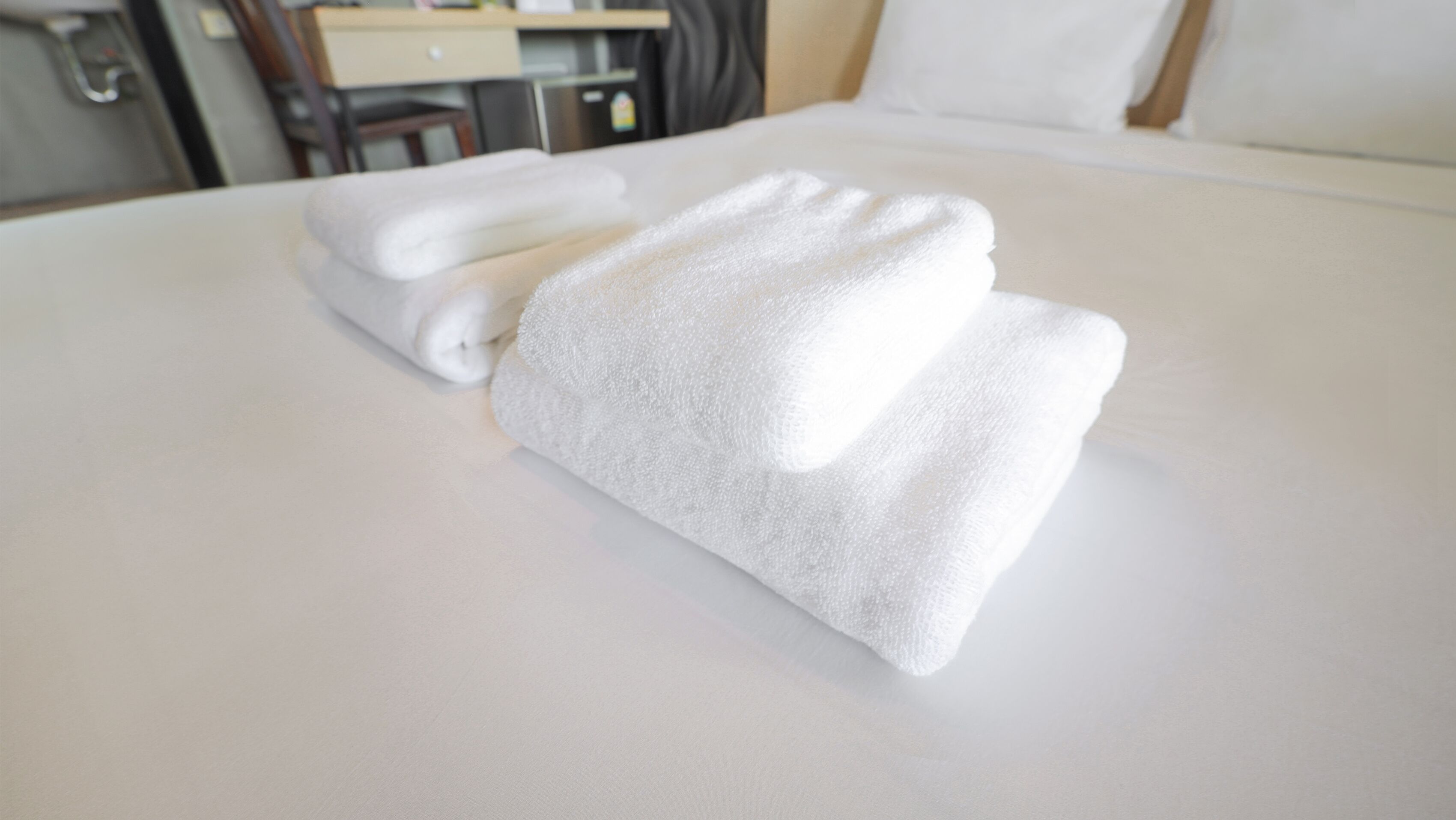 A neatly made bed with white linens and a folded towel.