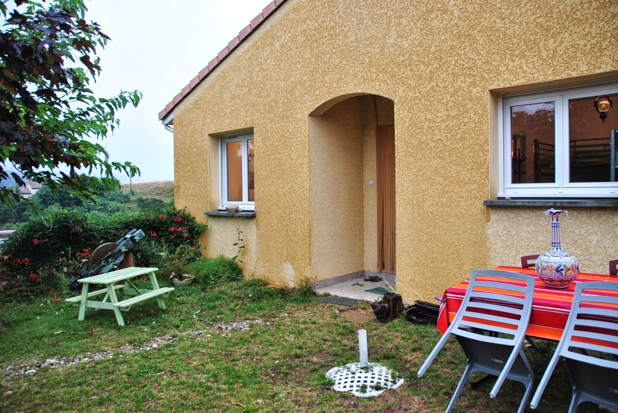 A yellow house with a small porch and a table with chairs outside.