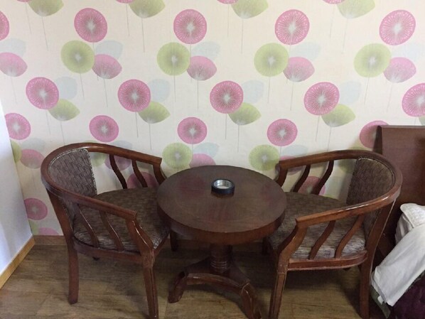 A dining area with a round wooden table and four wooden chairs with cushioned seats.