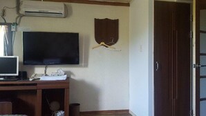 Habitació amb televisió de pantalla plana penjada a la paret, escriptori de fusta amb un ordinador i una ganxeta per a abrics a la paret.
