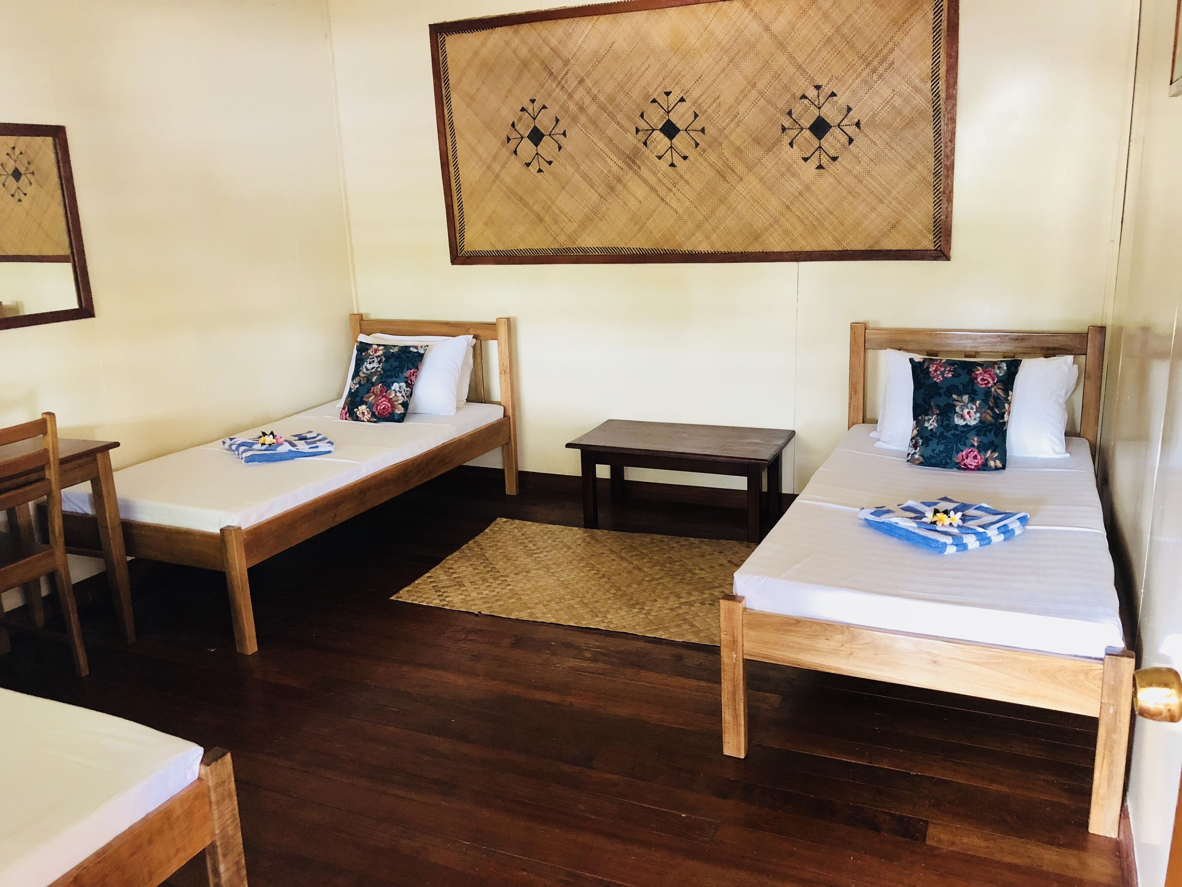 Una habitación con dos camas individuales, una mesita pequeña y una silla de madera.