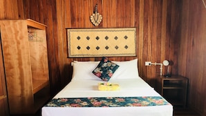 A wooden bed with a floral bedspread, white pillows, and a decorative headboard. - Qua Roviana Motel (Munda)