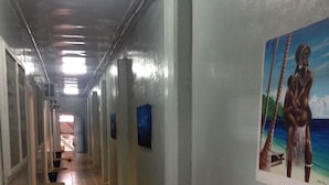 A long, narrow hallway with tiled floors and walls adorned with framed artwork. - Qua Roviana Motel (Munda)