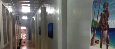 Un pasillo largo y estrecho con pisos de baldosas y paredes decoradas con cuadros.