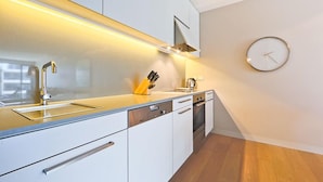 A modern kitchen with white cabinets, a stainless steel sink, and a built-in oven. - Accommodate Canberra - Aurora (Kingston)
