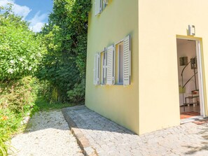 A yellow building with white shutters, a cobblestone path, and lush greenery. - Forest Hideaway Near Douro Valley (Abragão-Penafiel)
