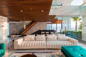 A modern living room with a large sofa, a coffee table, and a staircase leading to an upper level. - Maple Hotel & Apartment (Nha Trang)