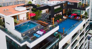 A rooftop pool area with a large pool, lounge chairs, and a glass balustrade. - Maple Hotel & Apartment (Nha Trang)