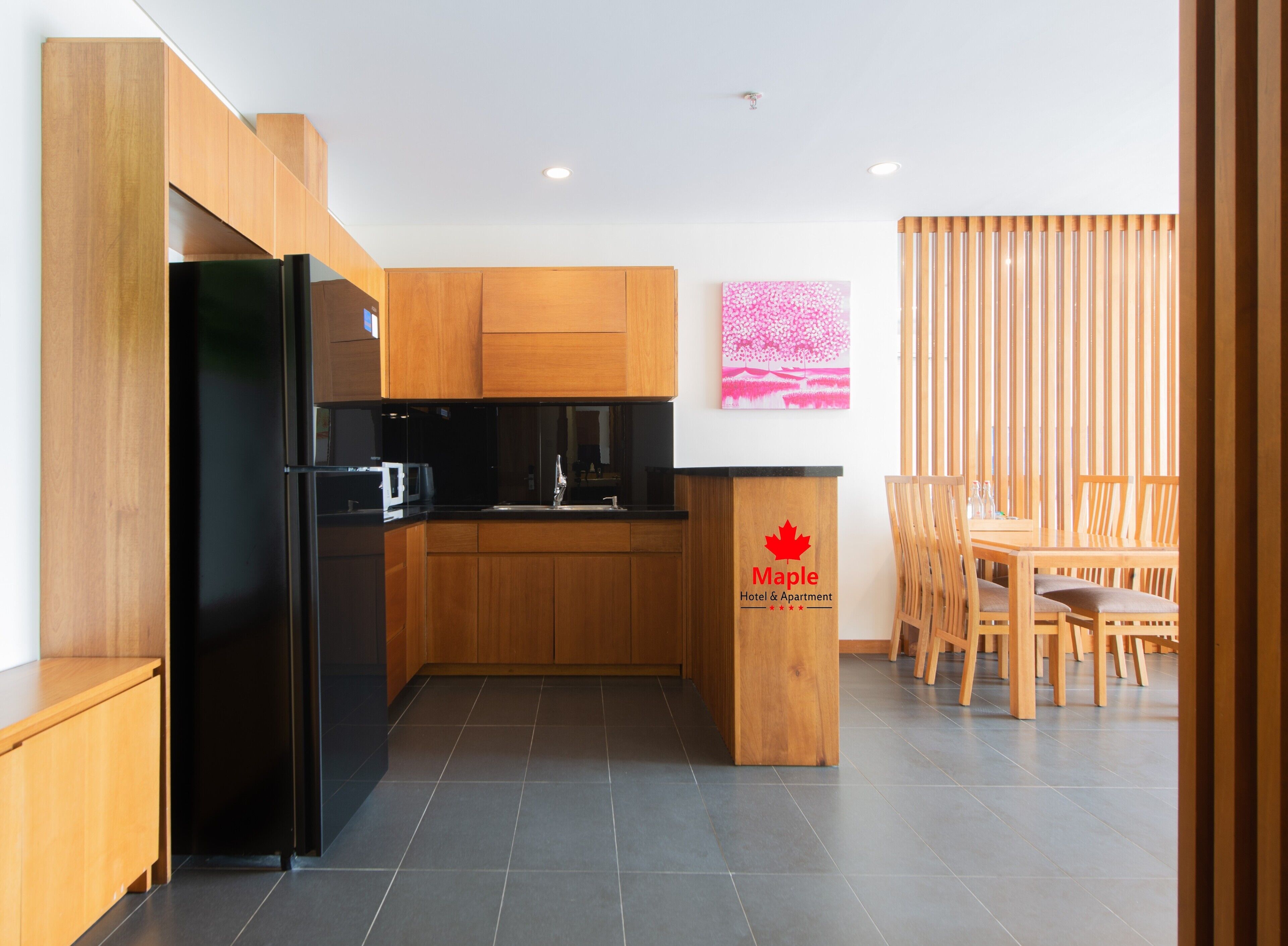 A modern kitchen with wooden cabinets, a black refrigerator, and a dining area with wooden chairs and a table.