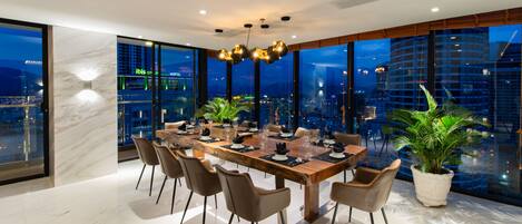 A modern dining area with a large table, chairs, and a city view.