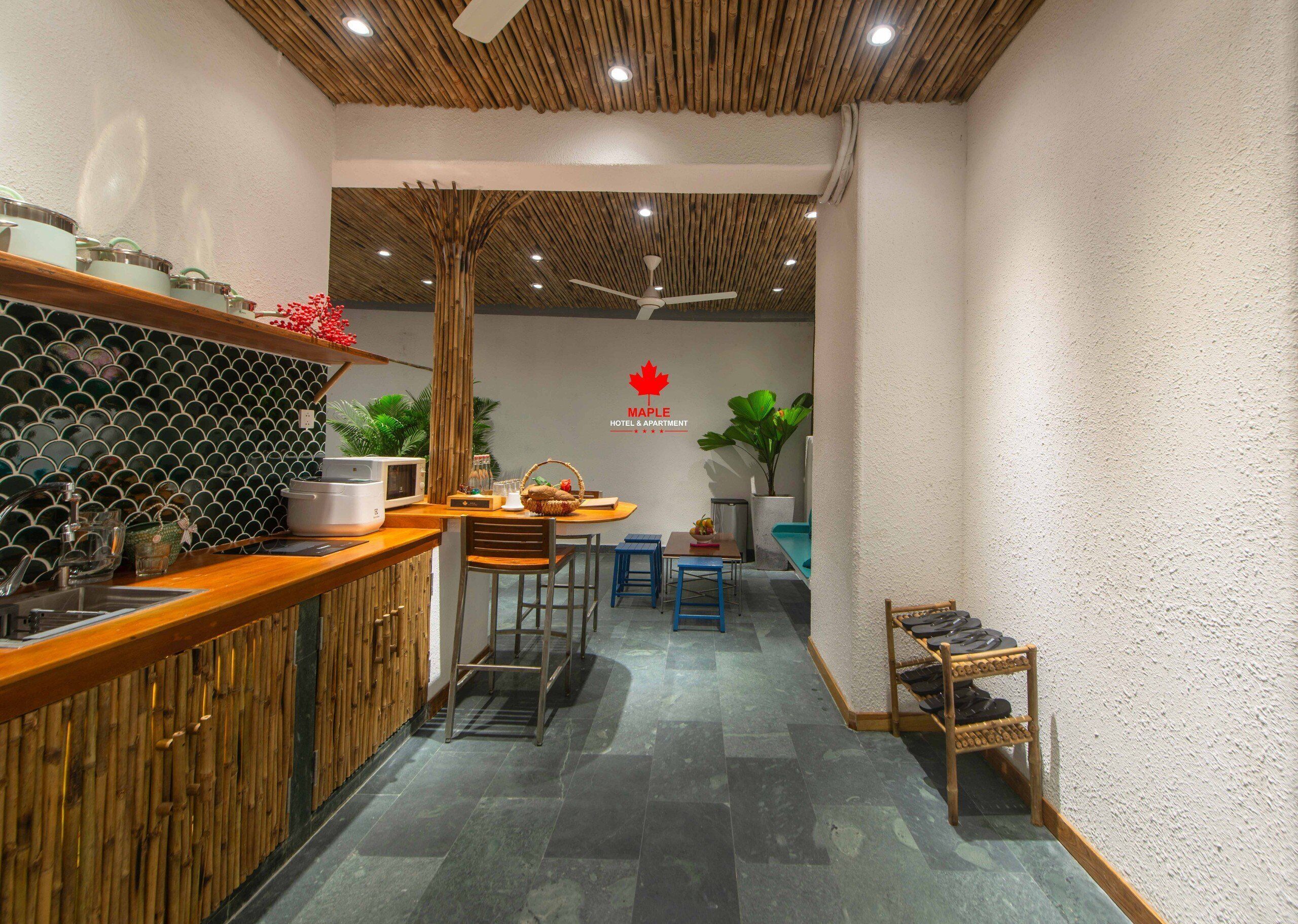 Una cocina de hotel compacta con mostrador de madera, un área de comedor con taburetes y un ventilador de techo.
